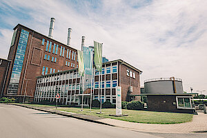Firmengebäude im Hintergrund mit Fahnen und Mast im Vordergrund 