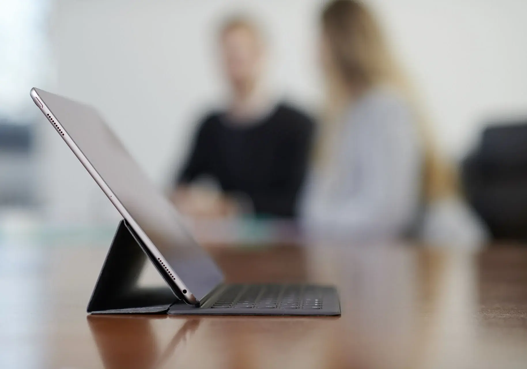 Tablet auf einem Tisch mit Mitarbeitern unscharf im Hintergrund